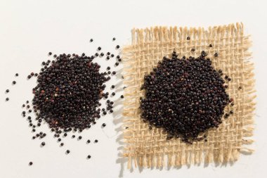Chenopodium kinoa, Kara kinoa tohumunun bilimsel adıdır. Tahıllar beyaz masanın üzerine yayılmış..