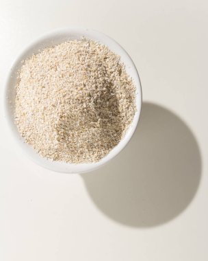 Avena Sativa, Yulaf gevreğinin bilimsel adıdır. Aveia ya da Avena olarak da bilinir. Kasedeki tahıllar. Beyaz masanın üzerindeki gölge.