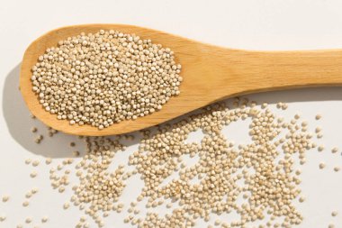 Chenopodium kinoa, Altın kinoa tohumunun bilimsel adıdır. Tahta kaşıkta sağlıklı taneler. Beyaz arkaplan.