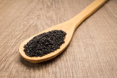 Sesamum radiatum, Benniseed 'in bilimsel adıdır. Ayrıca Black Susame, Gergelim Preto (Portekizce) ve Susamo Negro (İspanyolca) olarak da bilinir. Tahta masanın üzerinde kaşık ve tahıllar.