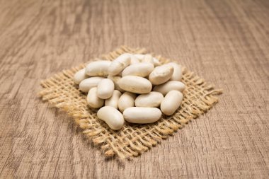 Phaseolus vulgaris, Donanma Fasulye Baklagil 'inin bilimsel adıdır. Haricot, Pearl Bean ve Feijao Branco olarak da bilinir. Kenevirin kare kesiminde tahıllar. Tahta masa. Seçici odak.
