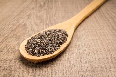 Salvia Hispanica, Chia Seed 'in bilimsel adıdır. Ayrıca Semente de Chia (Portekizce) olarak da bilinir. Tahta masanın üzerinde kaşık ve tahıllar.