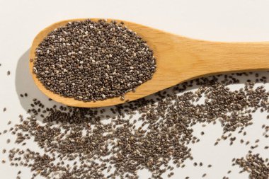 Salvia Hispanica, Chia Seed 'in bilimsel adıdır. Ayrıca Semente de Chia (Portekizce) olarak da bilinir. Tahta kaşıkta sağlıklı taneler. Beyaz arkaplan.