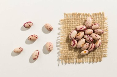 Fahseolus vulgaris, Şeker Fasulyesi baklasının bilimsel adıdır. Feijao Rajado ya da Frijol Canaval olarak da bilinir. Tahıllar beyaz masanın üzerine yayılmış..