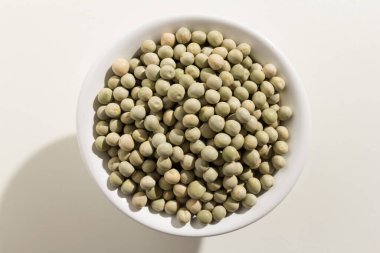 Pisum sativum, Bezelyenin bilimsel adıdır. Ayrıca Ervilha (Portekizce), Chicharo ve Arveja (İspanyolca) olarak da bilinir. Bir kasedeki tahılların üst görüntüsü. Beyaz arkaplan.