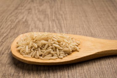 Oryza sativa, Çin pilav tohumunun bilimsel adıdır. Long Grain Rice ve Arroz Agulha Integral (Portekizce) olarak da bilinir. Tahta kaşıkta tahıllar. Kırsal.