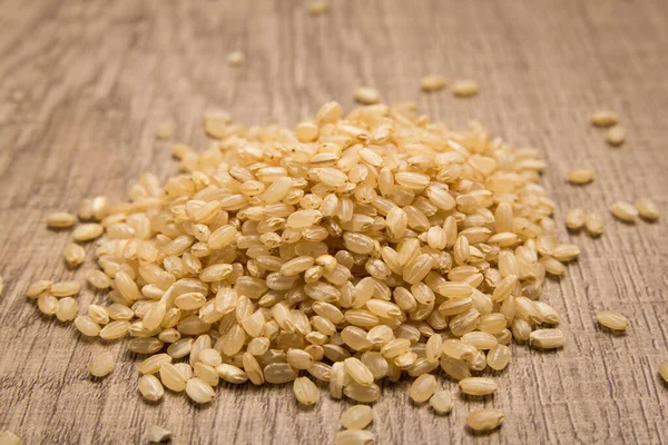 Oryza Sativa 是全麦稻种的科学名称 也被称为Sushi Rice和Arroz Cateto Integral 葡萄牙语 木桌上堆满了谷物 有选择的重点 — 图库照片