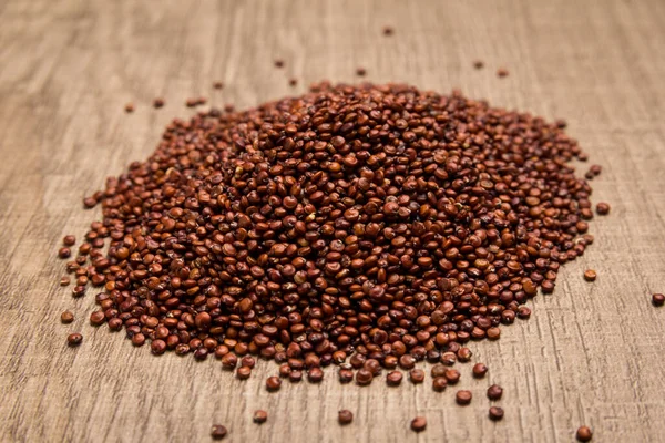 Chenopodiumキノアは紅キノアの種子の学名です 木製のテーブルの上に穀物の山 選択的焦点 — ストック写真