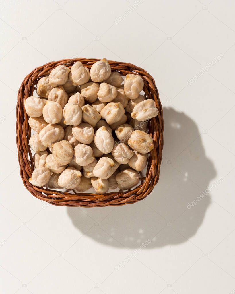 Cicer arietinum is scientific name of Chickpeas legume. Also known as Garbanzo bean, Chick Peas or Grao de Bico. Wicker basket with grains. Top view, hard light.