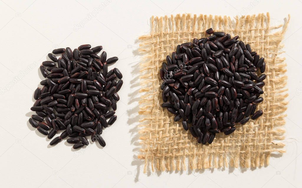 Oryza sativa is scientific name of Black Rice seed. Also known as Arroz Negro (portuguese). Close up of grains spreaded over white table.