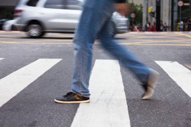 Yaya yolundan geçen bir adam var. Hareket tarafından bulanıklaştırılmış.