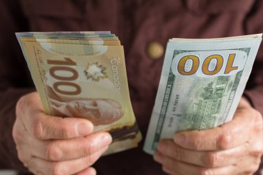 Kanada Doları ve Kuzey Amerika parası. Kanada ve Amerika 'dan gelen para. Öne bakan kişi fatura tutar.