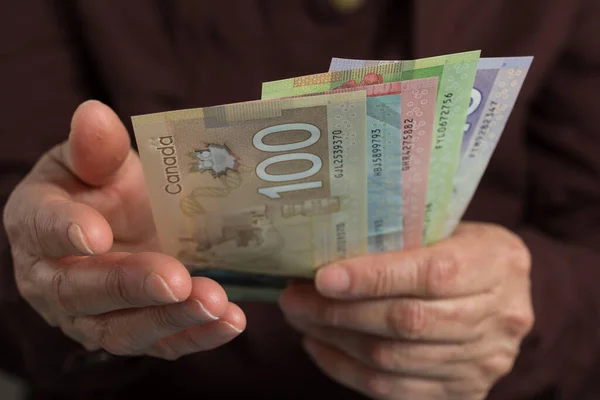 Money from Canada. Dollars. Canadian currency. Front view senior person holding bills.