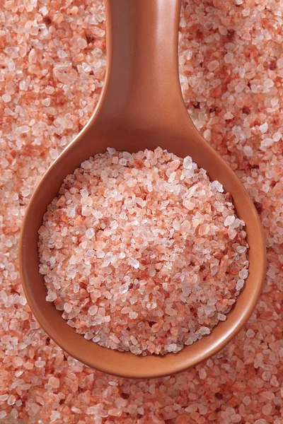 Pink Himalayan salt in spoon. Top view of spoon full of pink Himalayan salt on salt crystal.