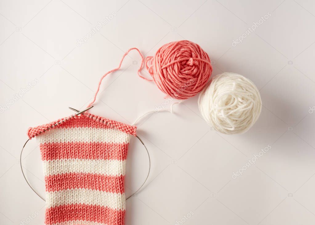 knitting stripes with two colors of yarn on wooden table