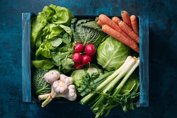 暗い青い表面に新鮮な有機野菜でいっぱい木箱 — ストック写真