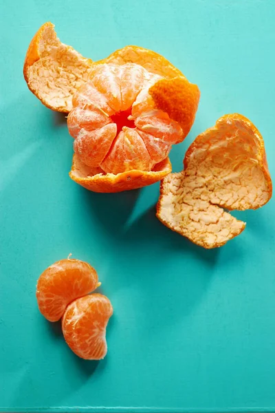 Una Mandarina Parcialmente Pelada Sobre Fondo Verde Azulado —  Fotos de Stock