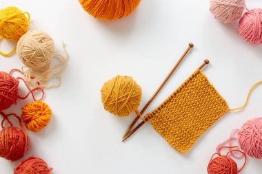 Örgü projesi devam ediyor. İplik yumağı ve örgü iğneleriyle örülmüş bir örgü parçası..