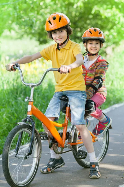 En liten flicka och pojke cyklar — Stockfoto