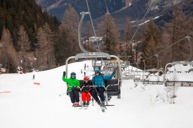 Baba ve iki çocuk Avrupa kayak merkezi asansörde sandalye üzerinde oturan.