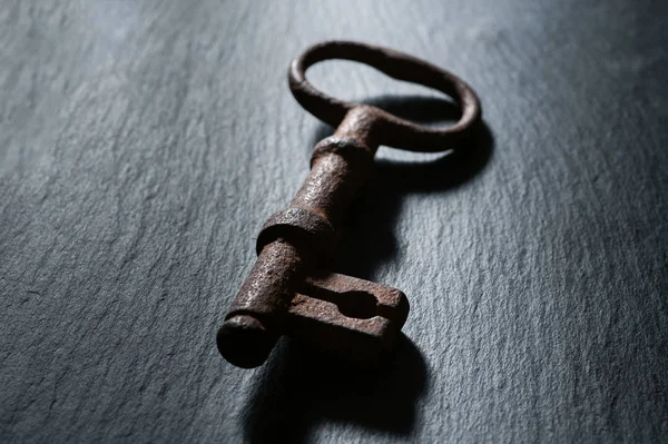 Vieja llave oxidada de un viejo candado se encuentra sobre un fondo negro —  Fotos de Stock