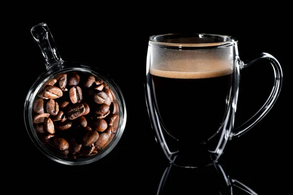 Composition of two coffee mugs. left coffee beans in a glass cup top view, right coffee in a glass cup side view. Black background — Stock Photo, Image