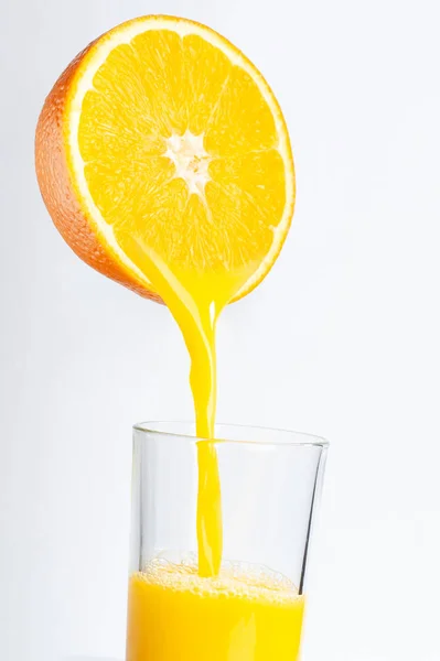 Frischer Orangensaft wird aus einer halben Orange in ein transparentes Glas gegossen. Platz für die Inschrift — Stockfoto