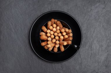  Ekmek kırıntıları olan siyah seramik bardak servis edilen siyah tahta üzerinde duruyor.