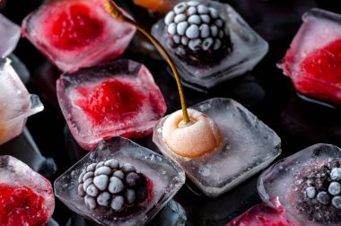  frozen raspberries berries cherries and blackberries in pieces of ice in a glass bowl on a black background clipart