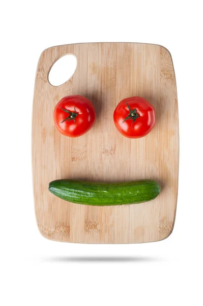 Свежие овощные помидоры и огурец в виде смешного лица на разделочной доске. изолировать на белом фоне — стоковое фото