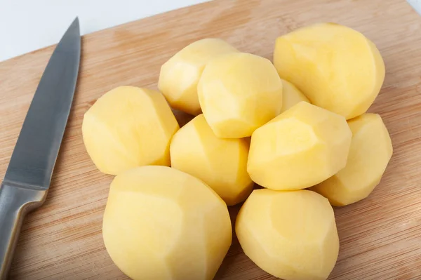 Geschälte Kartoffeln liegen auf einem Küchenholzschneidebrett. isolieren auf weißem Hintergrund — Stockfoto