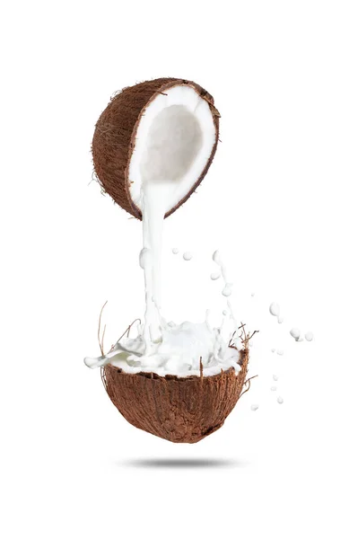 La leche de coco blanco con salpicaduras se vierte de una mitad de coco a otro. aislado sobre fondo blanco — Foto de Stock