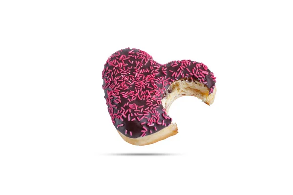 Zoete chocolade-gecoate donut met een roze strooi in de vorm van een hart gebeten aan de ene kant geïsoleerd op een witte achtergrond — Stockfoto