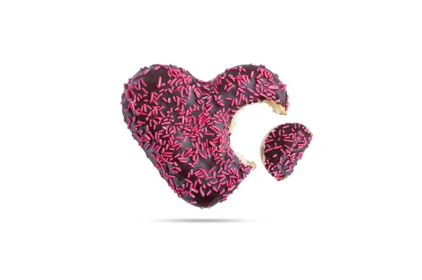  Bir tarafından ısırılmış pembe bir kalp şeklinde serpiştirilmiş çikolata kaplı donut beyaz bir arka planda izole edilmiş.