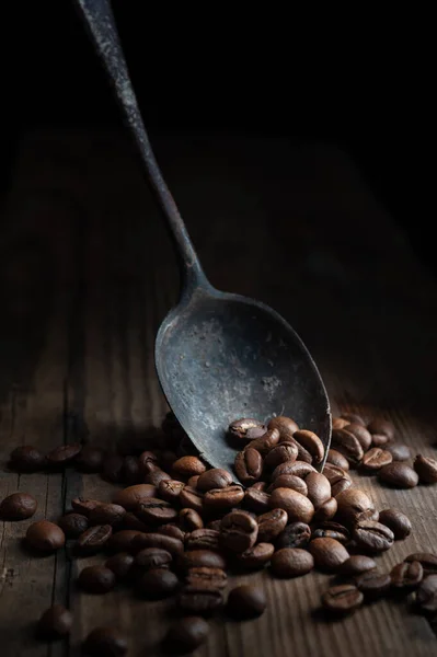 Grains de café sur vieille cuillère rouillée sur fond en bois — Photo