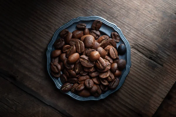 Grains de café sur une assiette sur un fond en bois — Photo