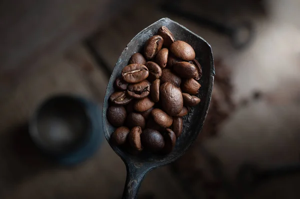 Grains de café sur vieille cuillère rouillée sur fond en bois — Photo