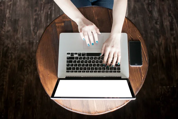 Mockup görüntüsünü kullanarak ve boş beyaz ekran ve modern loft kafede masada kahve fincanı ile laptop yazarak iş kadını