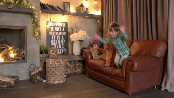 Dos niños pequeños saltando del sofá — Vídeo de stock