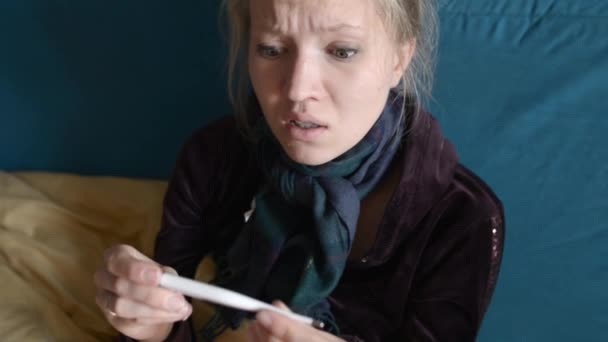 En ung kvinna tittar på vittnesmål från en elektronisk termometer — Stockvideo