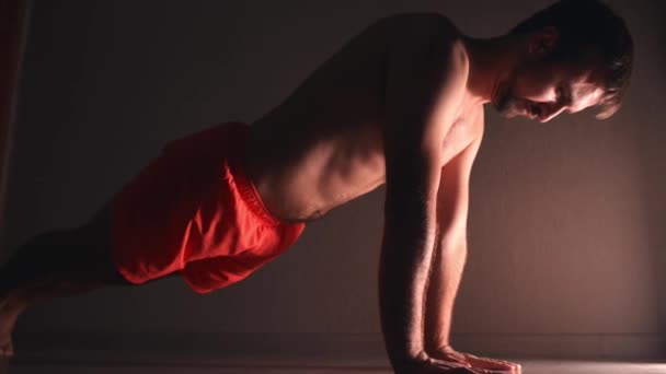 Man in orange shorts try to do plank exercise at home — 비디오