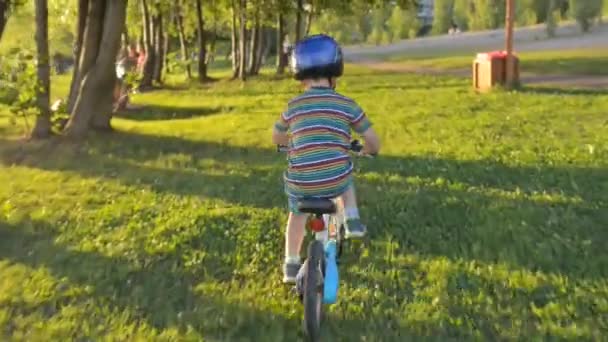 Niño montar en bicicleta en la hierba con casco — Vídeo de stock