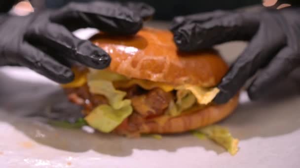 Καυκάσια ελκυστική ξανθιά γυναίκα απολαμβάνουν το φαγητό μεγάλο φρέσκο burger με όρεξη — Αρχείο Βίντεο