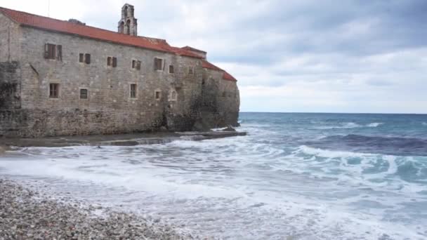 Море в облачную погоду большие волны бьются о каменную стену — стоковое видео