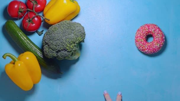 Kadın eli donut ve sebze arasında seçim yapar ve taze biber almaya karar verir. — Stok video