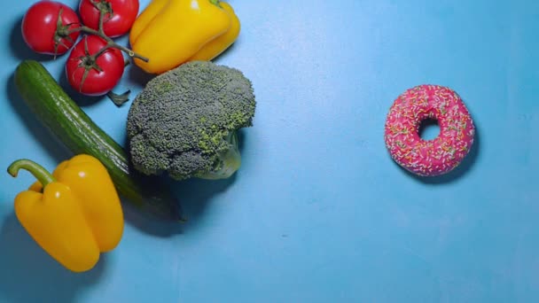La mano femenina elige entre comida sana y comida chatarra y decide tomar donut — Vídeo de stock