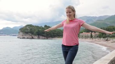 Deniz kıyısındaki korkulukta yürüyen çekici genç bir kadın.