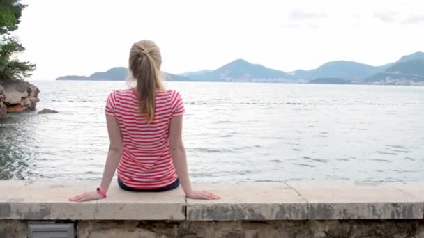 Vista trasera de la chica mirando al mar — Vídeo de stock