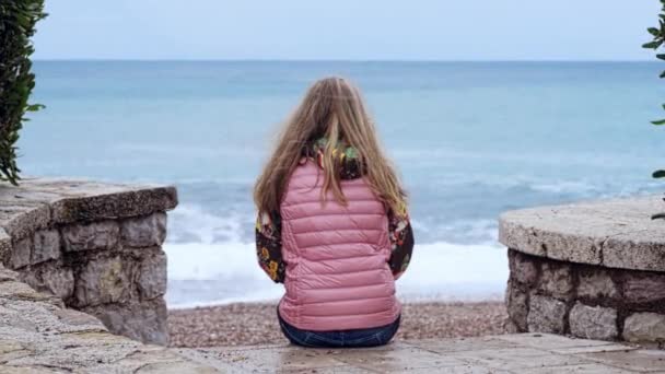 Samotna dziewczyna siedząca na schodach nad morzem Wideo Stockowe bez tantiem