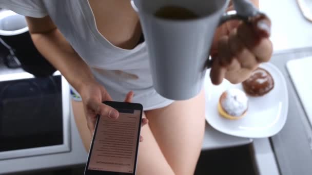 Junge Frau hält eine Tasse Kaffee und ein Smartphone in der Hand — Stockvideo